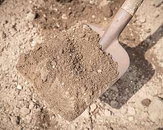 Nahaufnahme einer Schaufel mit Erde im Gartenboden