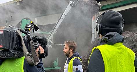 Ein Reporter interviewt einen Mann in einer rauchigen Umgebung.
