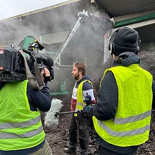 Ein Reporter interviewt einen Mann in einer rauchigen Umgebung.