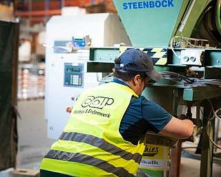 Mann mit Warnweste arbeitet an Maschine in Industrieumgebung