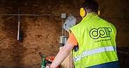 Person mit gelber Warnweste und Gehörschutz arbeitet an Maschine in Industrieumgebung
