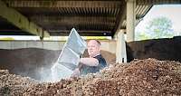 Mann schaufelt Erde oder Kompost in einer überdachten Lagerhalle