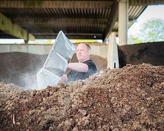 Mann schaufelt Erde mit großer Metallschaufel in einer Halle